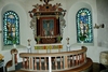 Tärby kyrkas kor med altaruppsats, glasmålningar från 1933 och altarring.