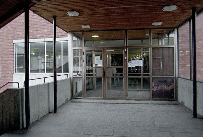 Entrén från Bredängstorget, vindfång i glas och koppareloxerad aluminium. På motsatt sida finns entrén till biblioteket.

 SAK00037_ Stockholm, Bredäng, Concordia 5, Bredängstorget 13-25,Concordiavägen 7-25_från väst