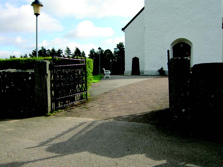 Kyrkogårdens huvudentré som leder in mot kyrkans entré.