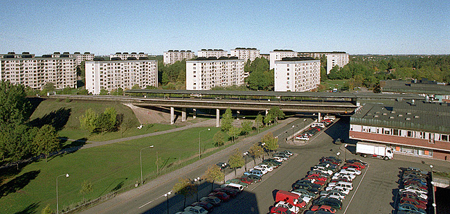 SAK00094 Stockholm, Bredäng, Gula knapparna 1- 2 och Frimurareorden 1, i bakgrunden Neptuniorden 1 och Amarantern 1-3. Fr. so .I det lummiga parklandskapet reser sig skivhusen som vitskimrande skulpturer. Vy över norra Bredäng från sydöst. Till höger en av centrumbyggnaderna.